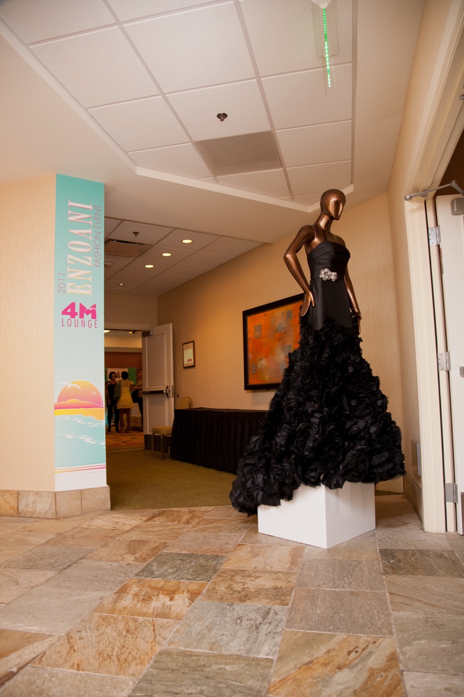 Enzoani 4M Lounge column signage beside a black couture gown on a plinth